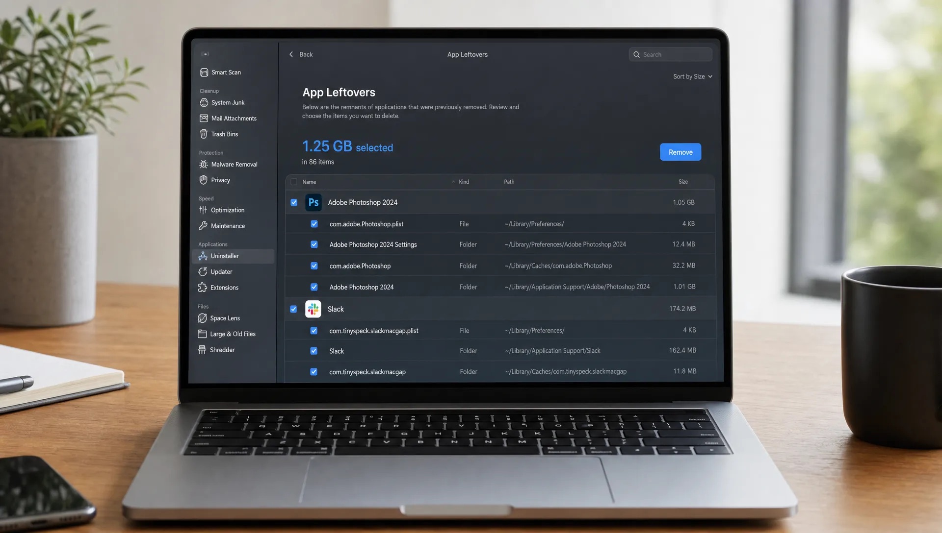 A MacBook on a desk shows app leftovers, folder paths and cleanup details being reviewed before removal.