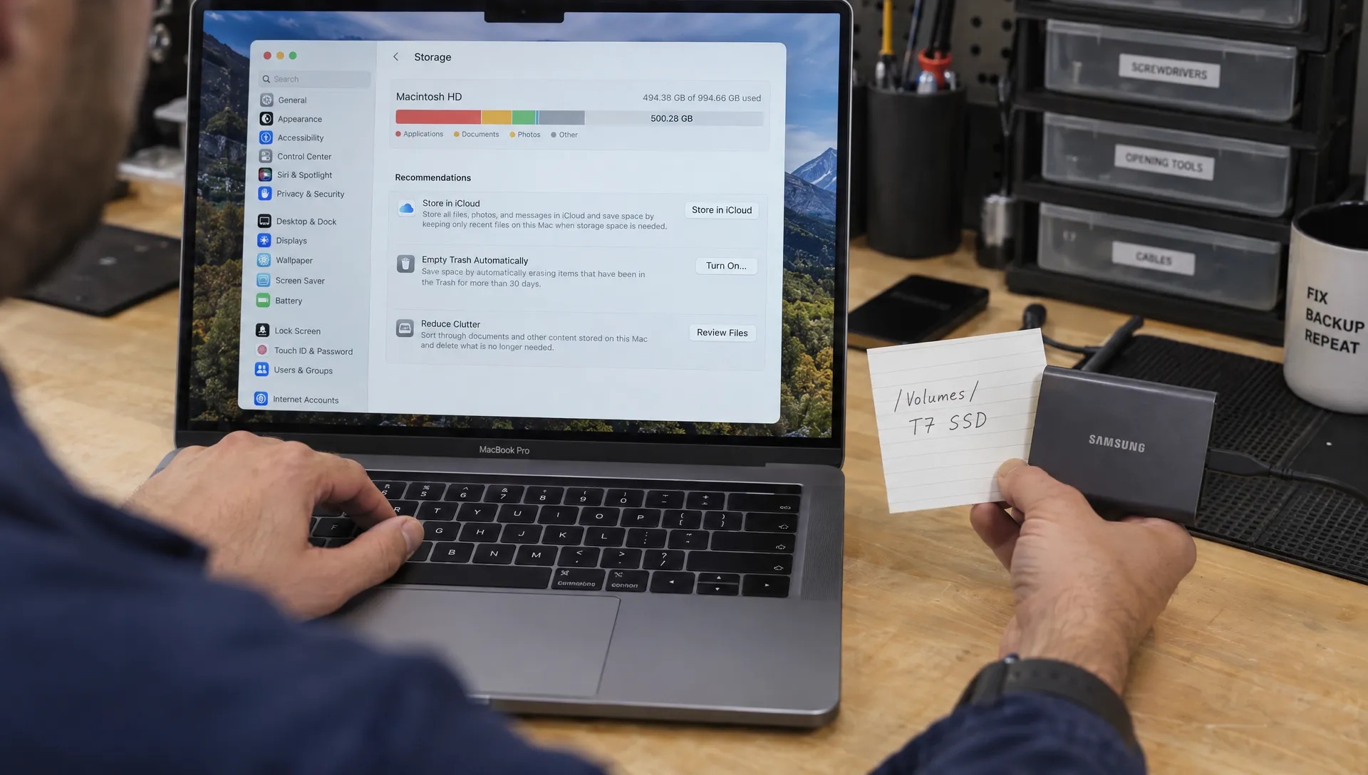 Hands compare a Mac storage map with a file-path note and external drive while checking cleanup candidates.