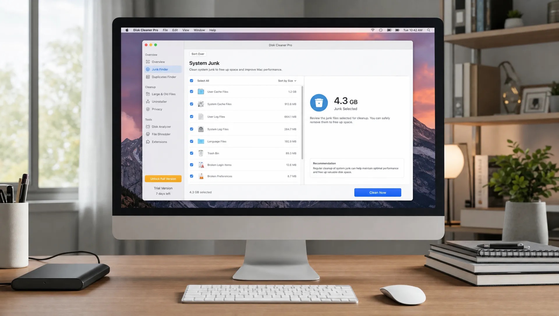 A desktop Mac setup shows a cleanup app with an external drive, keyboard and notebooks nearby as someone evaluates a free trial.