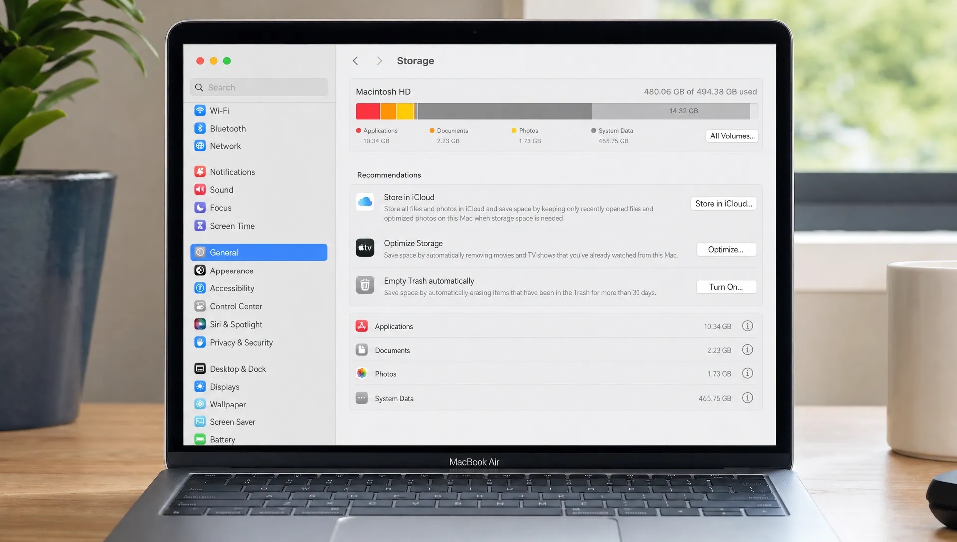 A MacBook screen shows storage usage with System Data taking up most of the space on a desk.